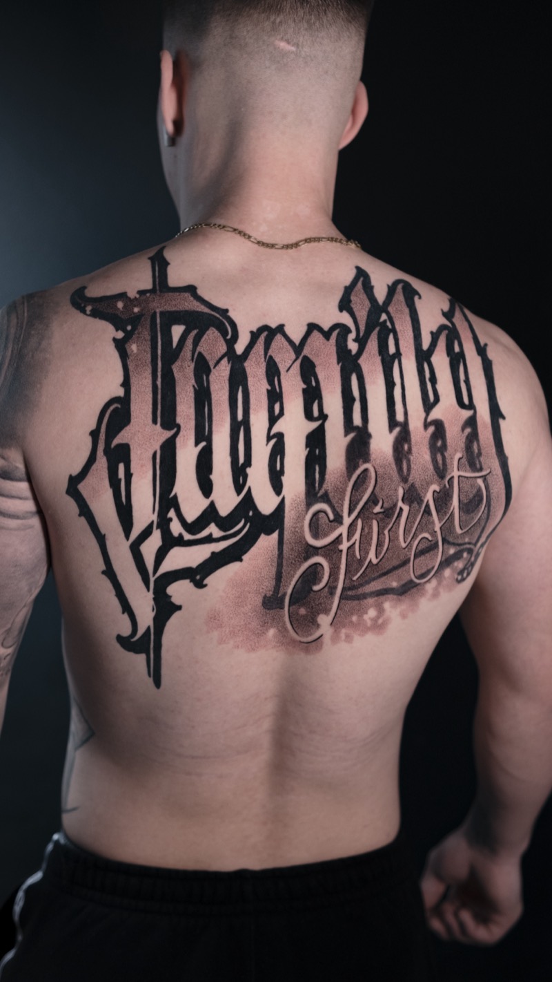 Rücken-Tattoo: Schriftzug „Family First“ in Blackletter und Script mit weicher Schattierung
